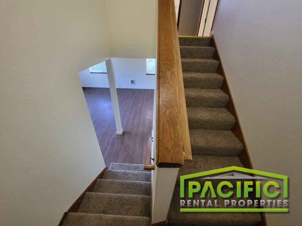 a view down the stairs of a house with a pacific rental properties sign on