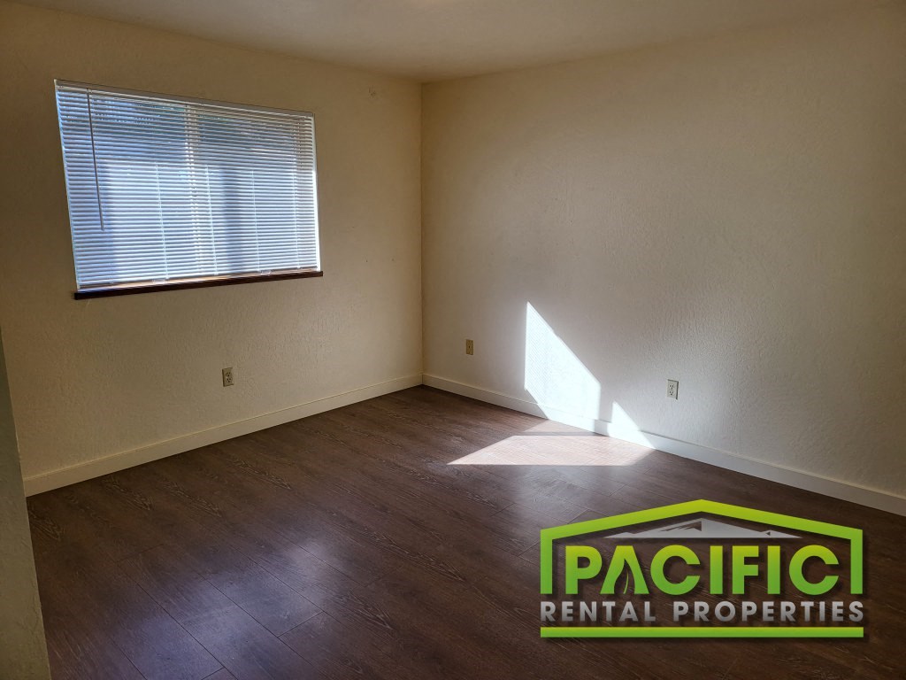 the living room of an empty house with wooden floors and a window
