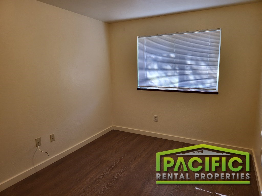 an empty room with a window and a pacific rental properties logo on the floor