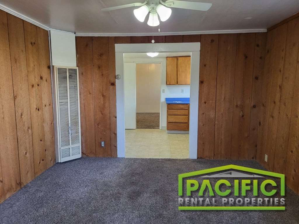 a room with a carpeted floor and a door to a kitchen