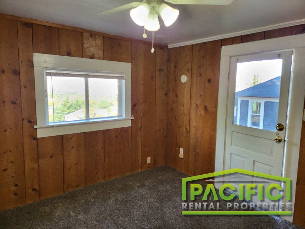 the bedroom of a house with wood paneling and a white door and window