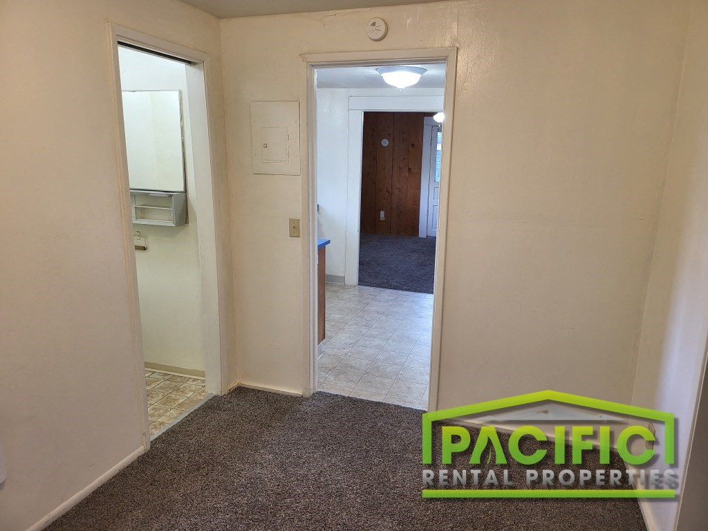 a small hallway with a door to a bathroom and a hallway leading into a bedroom