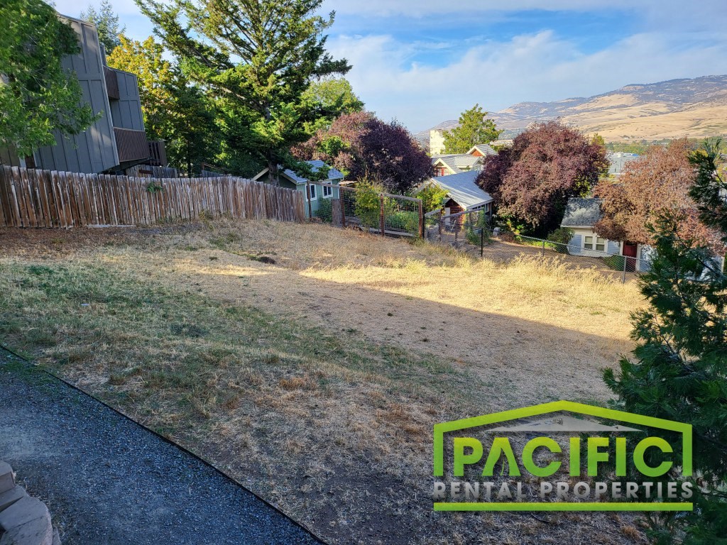 a backyard with a dirt road and a fence