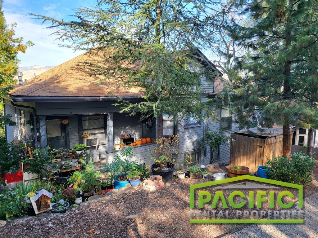 a backyard with a house and plants in front of it