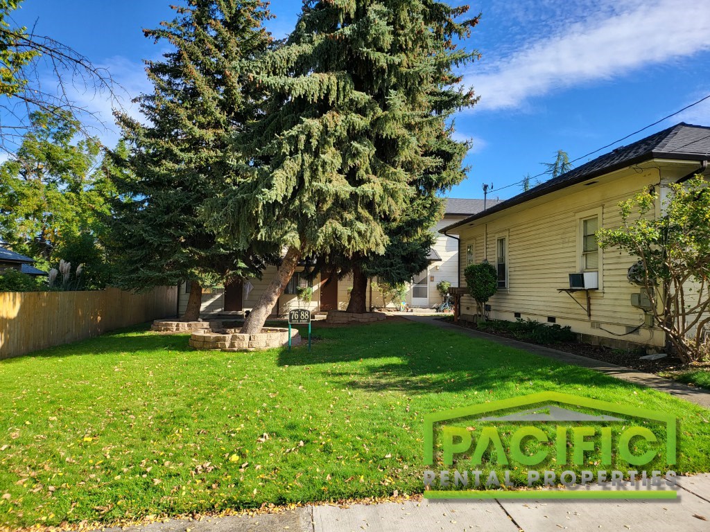 a backyard with a tree and a yellow house