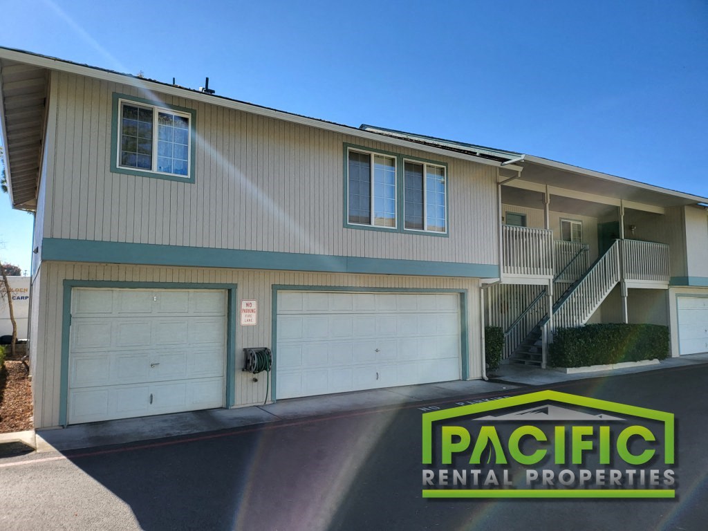 a building with two garage doors and a pacific rental properties sign