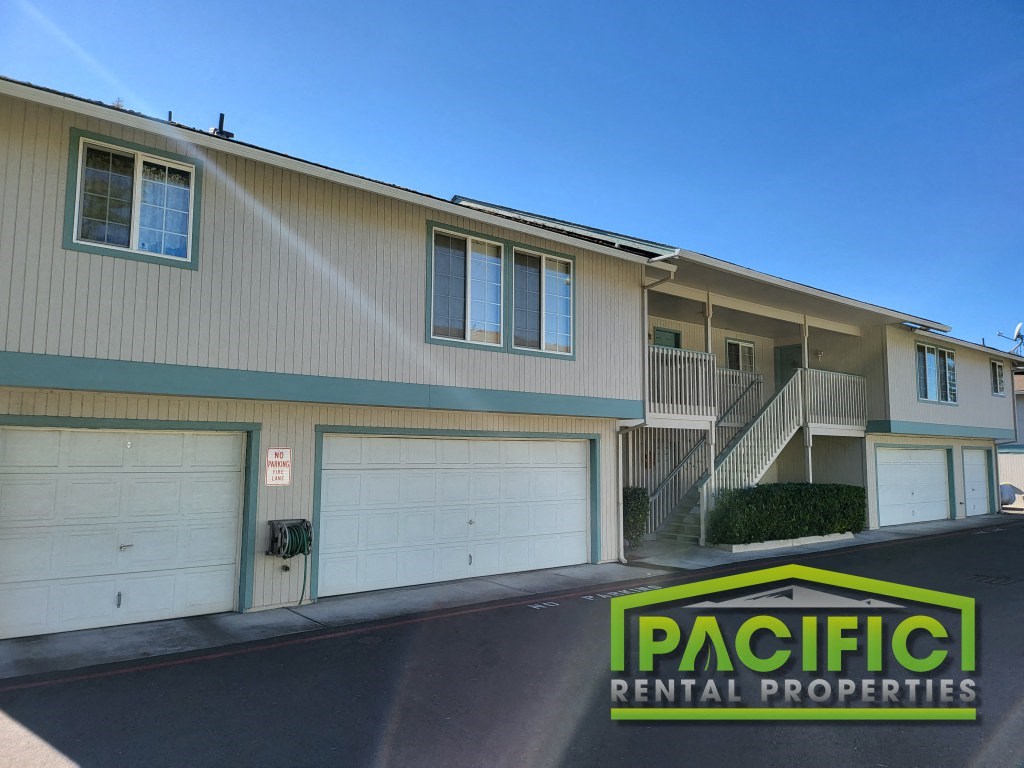 a building with two garage doors and a pacific rental properties sign