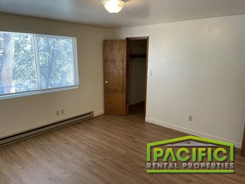an empty living room with wooden floors and a window
