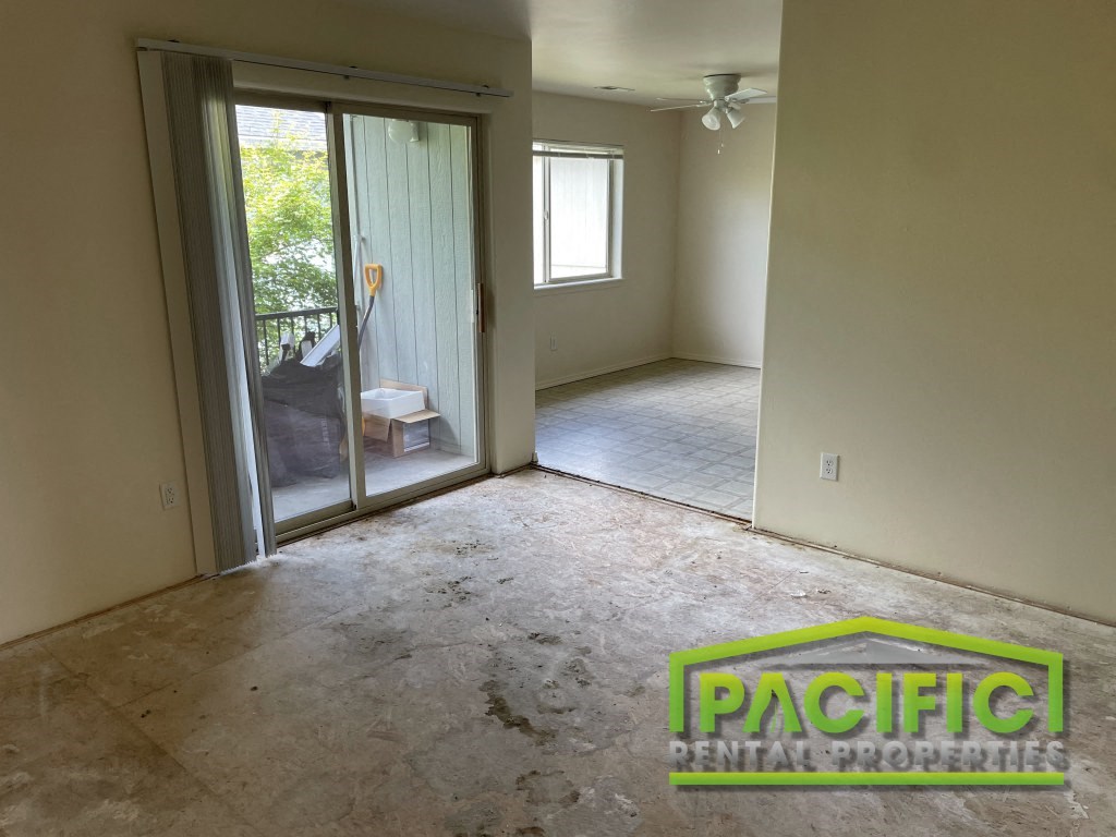 an empty living room with a sliding glass door to a patio