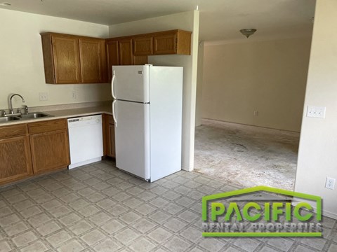 an empty kitchen with a white refrigerator and wooden cabinets