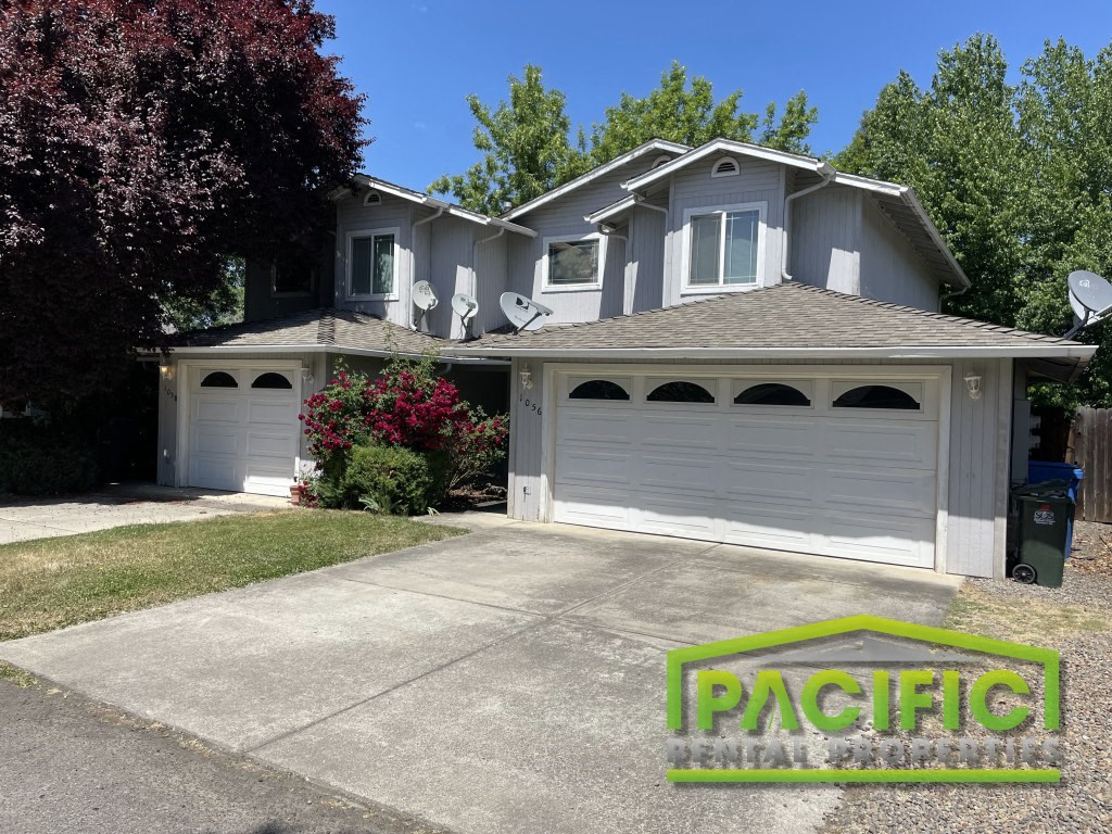A house with a garage and a tree in front of it.