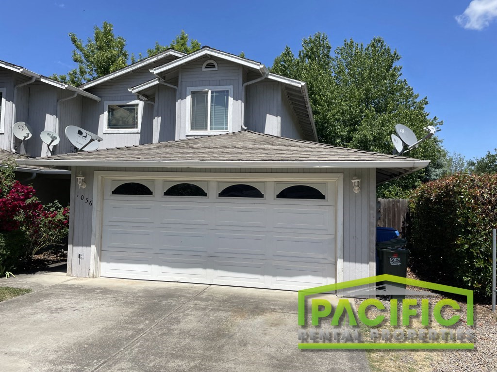 A house with a garage door and a sign that says "Pacific Rental Properties".