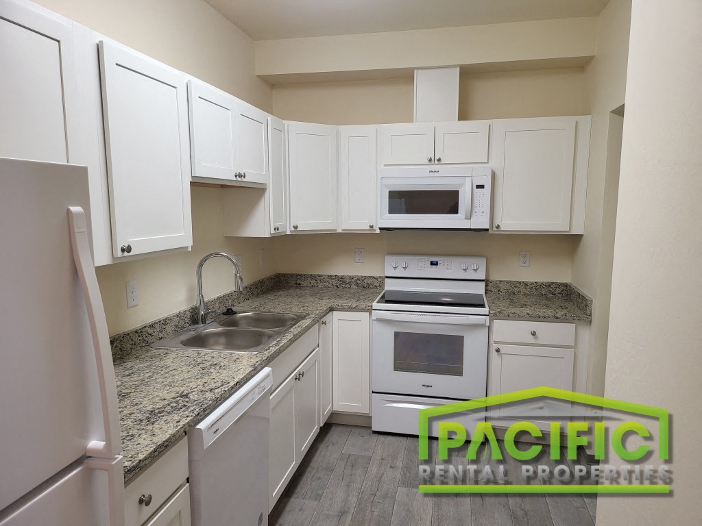 a white kitchen with granite counter tops and white cabinets