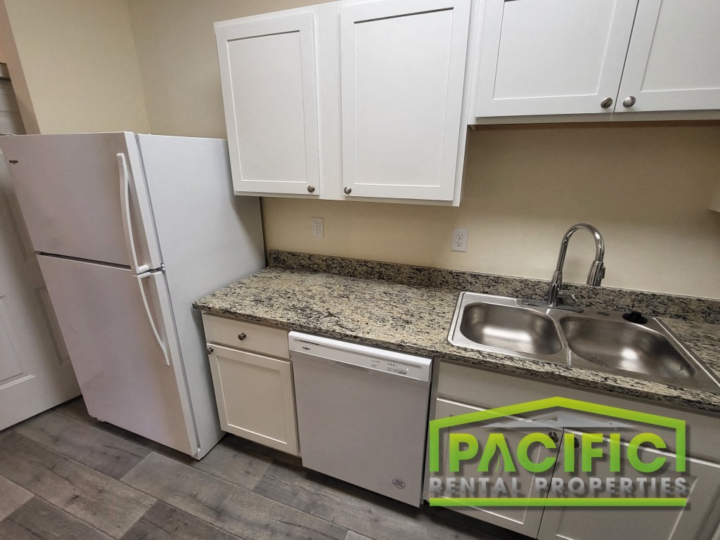 a kitchen with white cabinets and a sink and a refrigerator