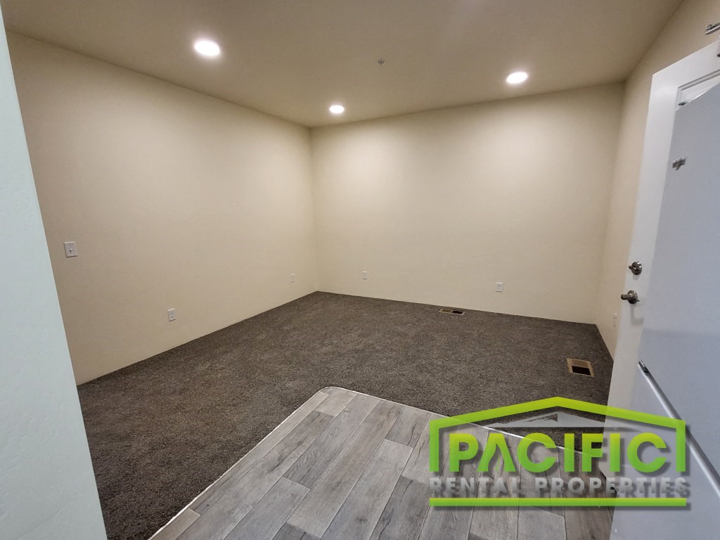 a room with a carpeted floor and a white wall and a door