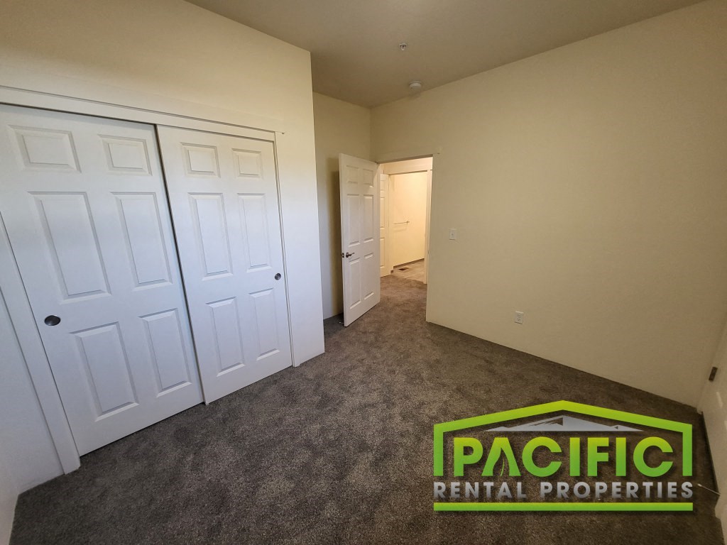 a bedroom with a closet and a door and a carpeted floor