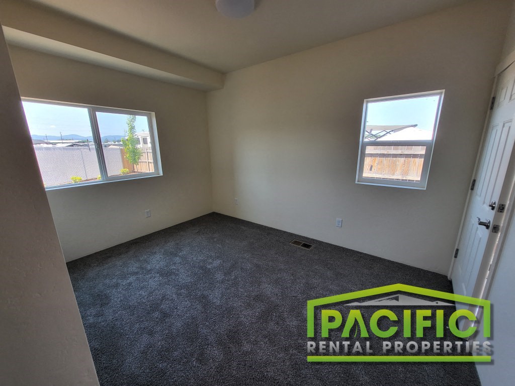 an empty room with a carpeted floor and two windows