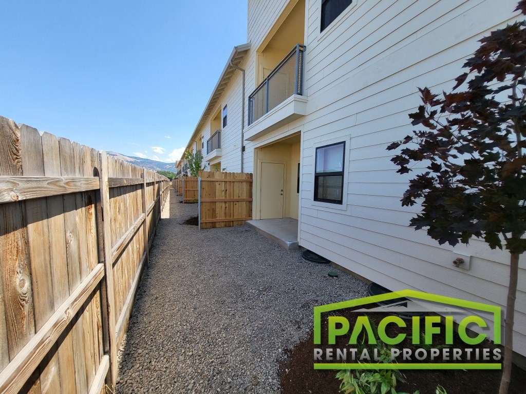 a walkway in front of a house with a wooden fence