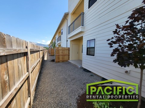a walkway in front of a house with a wooden fence