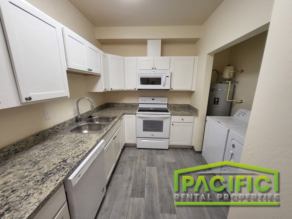 a renovated kitchen with white cabinets and granite counter tops