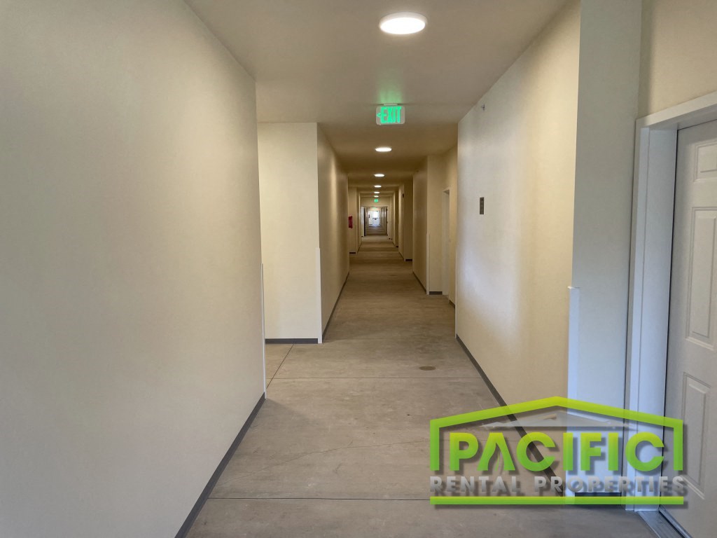 a long hallway with white walls and a green sign on the floor