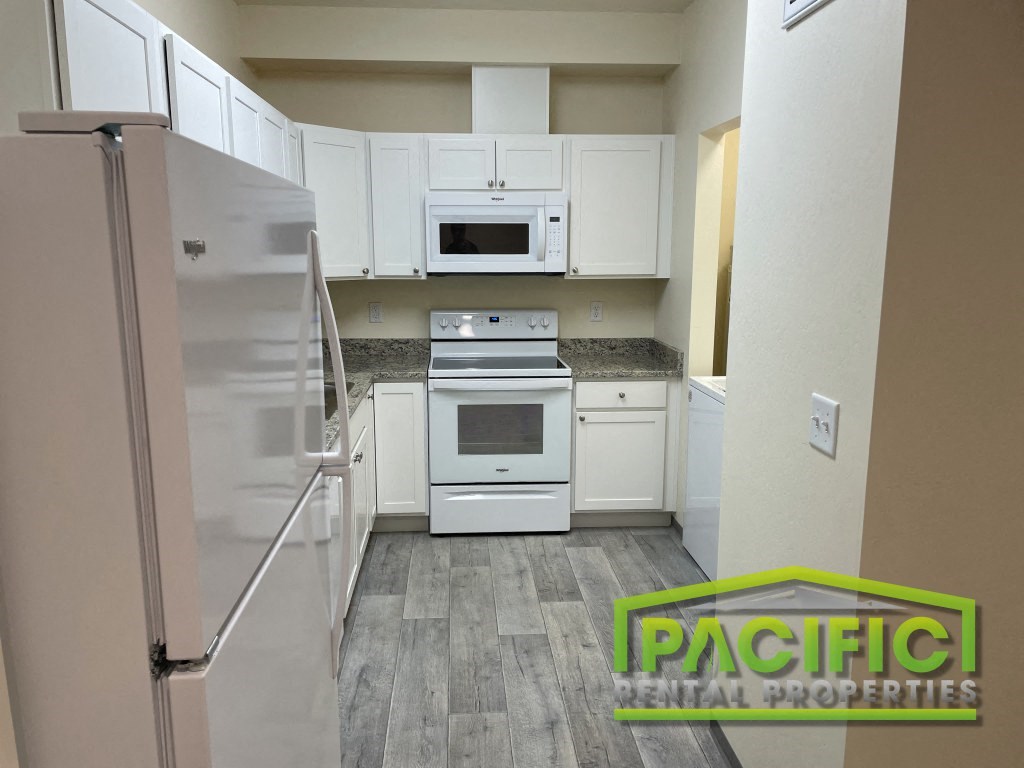 a kitchen with white cabinets and appliances and a refrigerator