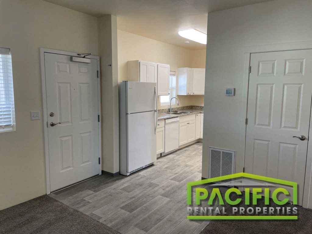 a renovated kitchen with white cabinets and a refrigerator  and a door