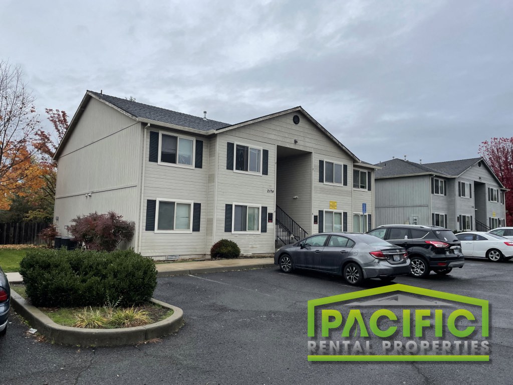a white apartment building with cars parked in a parking lot