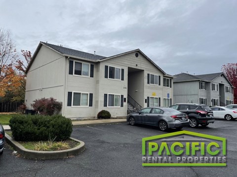 a white apartment building with cars parked in a parking lot