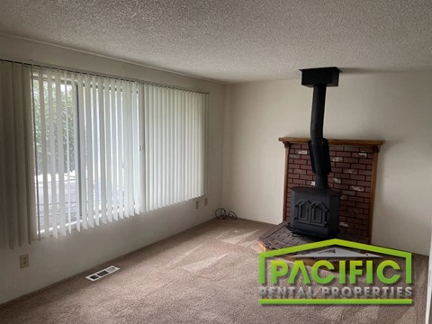 A living room with a fireplace and a window with blinds.