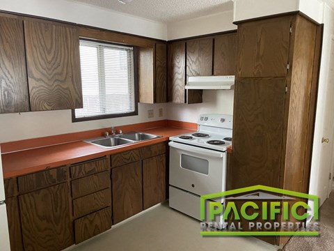 A kitchen with wooden cabinets and a stove top oven.