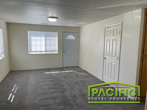 the living room of a house with carpet and a door