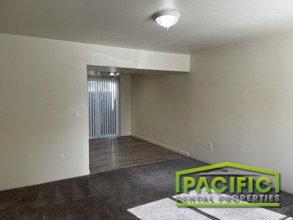 the living room of a new home with carpet and a door to the dining room