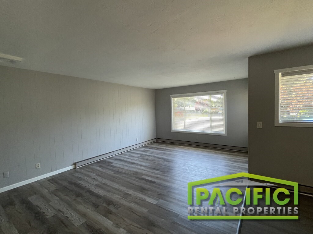 A room with wooden flooring and a window with blinds.