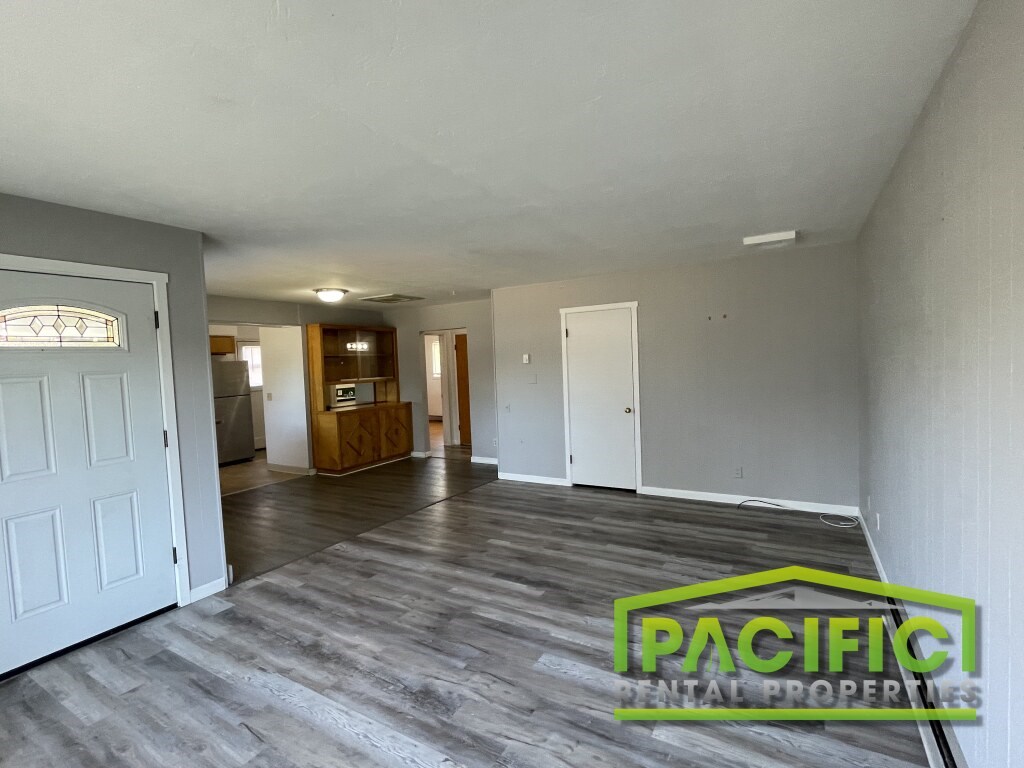 A spacious room with wooden flooring and a white door on the left.