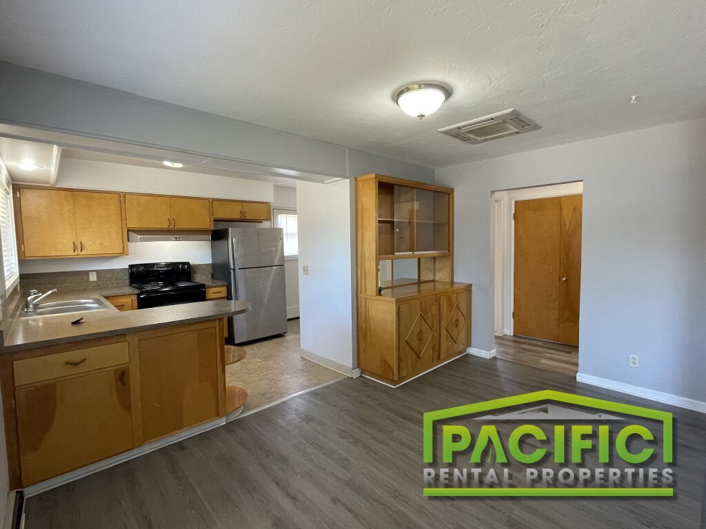A kitchen area with wooden cabinets and a refrigerator.