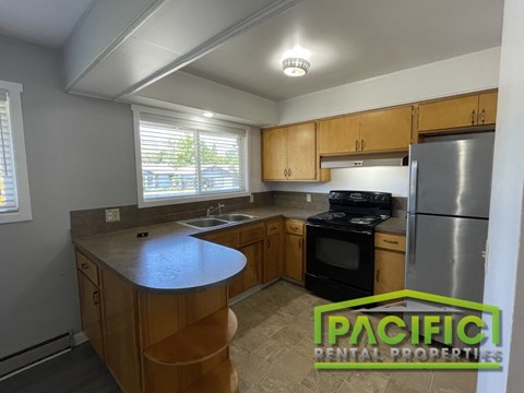A kitchen with wooden cabinets and a stainless steel refrigerator.