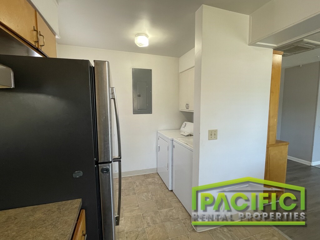 A black fridge in a kitchen with Pacific Rental Properties logo.