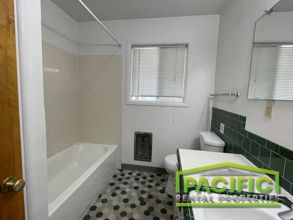 A bathroom with a bathtub, toilet, and sink.