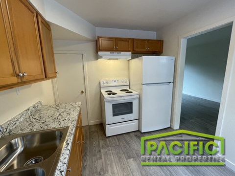 A kitchen with a sink, stove, and refrigerator.