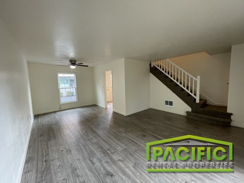 A spacious room with wooden flooring and a staircase leading to another level.