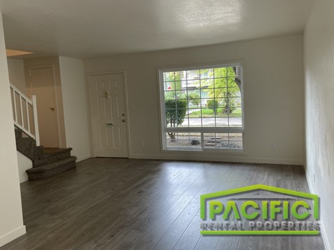 A room with wooden flooring and a window overlooking a patio.
