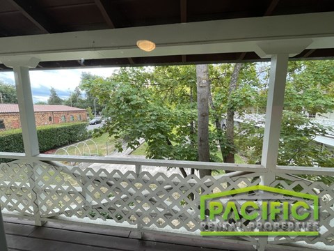 A balcony with a lattice design and a view of a backyard.