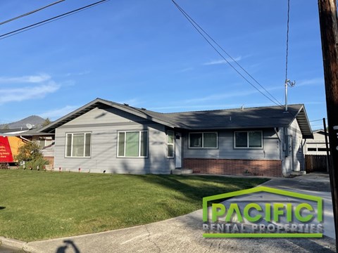 A house with a lawn in front and a sign that says Pacific Rental Properties.