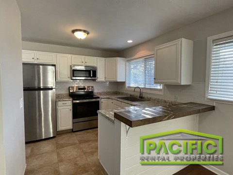 A kitchen with a refrigerator, microwave, oven, and sink.
