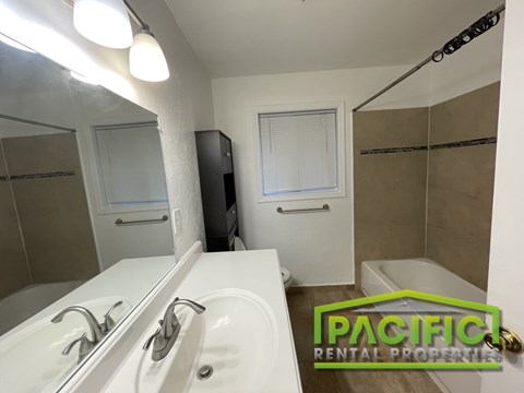 A bathroom with a white tub and a sink with a mirror above it.