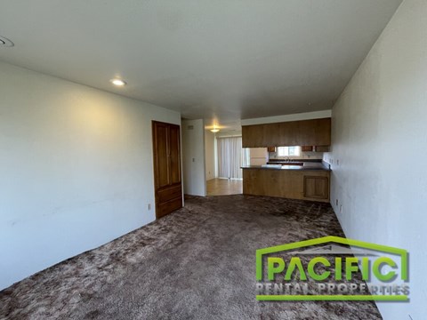 A spacious room with a carpeted floor and a wooden cabinet with a television on top.