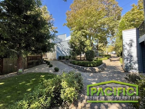 A lush green garden with a sign that reads "PACIFIC RENTAL PROPERTIES".