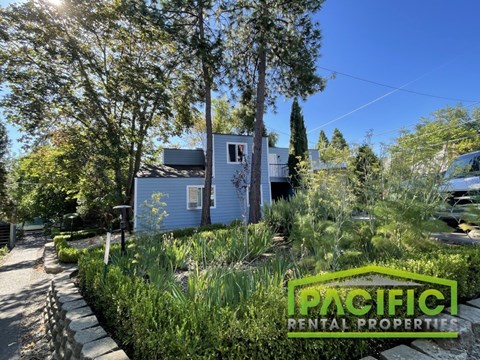 A blue house with a sign that says Pacific Rental Properties in front of it.