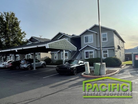 A parking lot with cars and a building with the sign "Pacific Rental Properties".